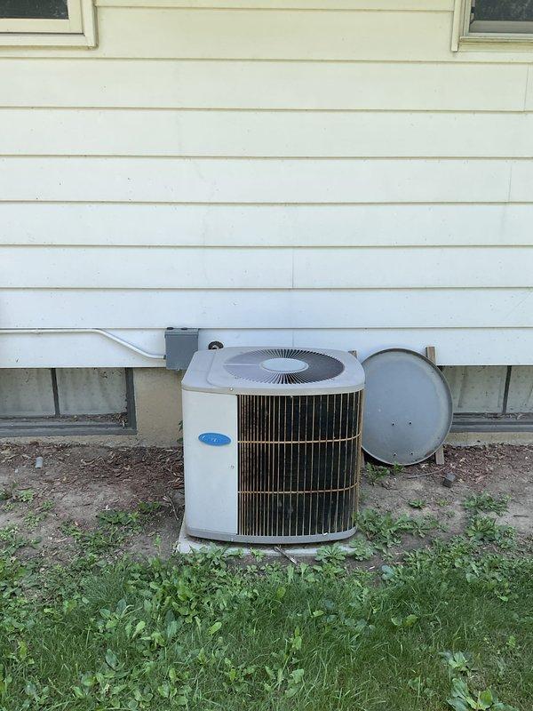 Provided replacement estimate for 20-year-old R22 residential HVAC system including outdoor condenser unit and Carrier gas furnace located in basement. Current system operational but at end of service life with obsolete refrigerant. Documented existing equipment configuration including refrigerant line routing, venting arrangement, and installation conditions for comprehensive replacement proposal.