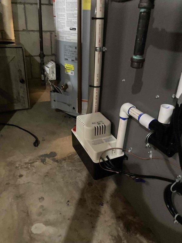 Completed prepaid annual air conditioner tune-up maintenance on outdoor AC unit. Performed comprehensive system inspection including electrical measurements using digital clamp meter, recording 880 AC amperage reading to verify proper compressor operation. Inspected indoor components including condensate pump system and drainage lines with PVC piping and fittings, confirming proper operation and drainage flow. All system parameters found within normal operating specifications with no issues identified during maintenance visit.