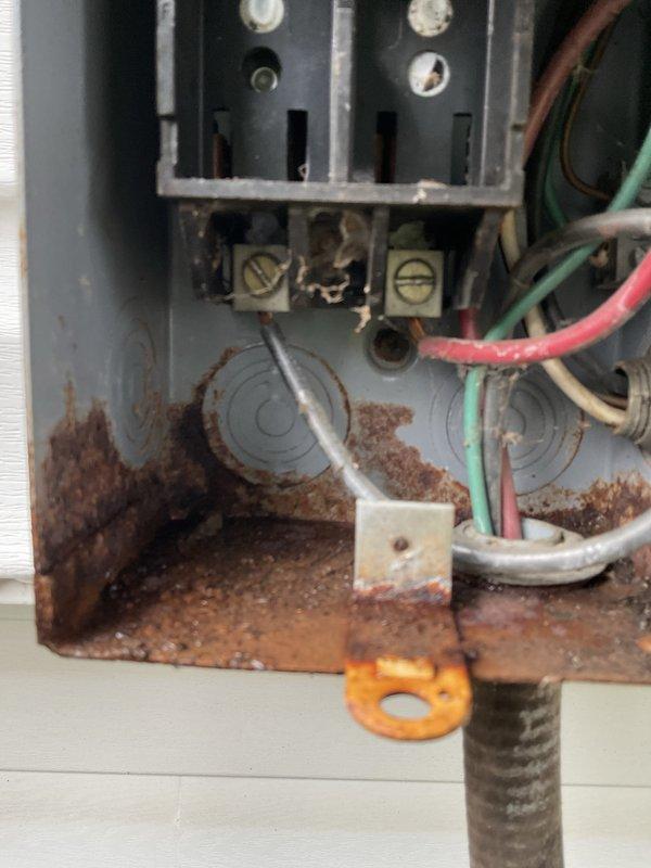 Completed routine maintenance and tune-up on a 20-year-old outdoor air conditioning system. Performed standard inspection procedures including checking system level, inspecting condenser coil fins, and evaluating overall unit operation. During inspection, discovered significant rust and corrosion damage within the electrical junction box, with heavy oxidation affecting the lower portion of the enclosure and spreading throughout the housing. Terminal blocks and wire connections remain intact, though the metal enclosure shows extensive deterioration consistent with long-term moisture exposure. Condenser unit exterior shows normal weathering for age, with dirt accumulation on fan motor housing and minor rust spotting on painted panels. Unit is operational with no immediate performance issues reported, however, the corroded electrical panel represents a potential safety concern and may require future attention to prevent electrical component failure or safety hazards.
