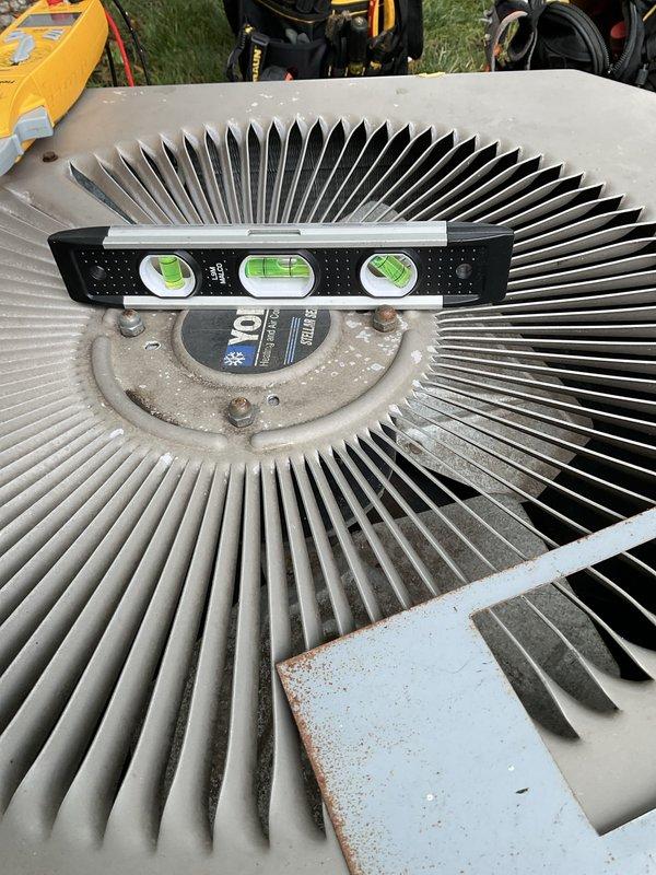 Completed routine maintenance and tune-up on a 20-year-old outdoor air conditioning system. Performed standard inspection procedures including checking system level, inspecting condenser coil fins, and evaluating overall unit operation. During inspection, discovered significant rust and corrosion damage within the electrical junction box, with heavy oxidation affecting the lower portion of the enclosure and spreading throughout the housing. Terminal blocks and wire connections remain intact, though the metal enclosure shows extensive deterioration consistent with long-term moisture exposure. Condenser unit exterior shows normal weathering for age, with dirt accumulation on fan motor housing and minor rust spotting on painted panels. Unit is operational with no immediate performance issues reported, however, the corroded electrical panel represents a potential safety concern and may require future attention to prevent electrical component failure or safety hazards.