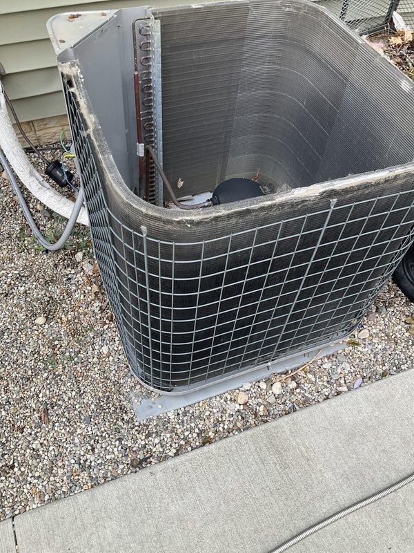 # HVAC Maintenance - Agreement Visit AC&SI

Completed comprehensive annual air conditioning tune-up and preventive maintenance on outdoor condensing unit per prepaid maintenance agreement. Unit is an older model AC system with black protective cage enclosure, positioned on concrete pad with gravel landscaping beside residence.

## Work Performed

Upon arrival, conducted visual inspection of outdoor condenser unit. Noted significant accumulation of leaves, twigs, and organic debris in base drain pan and around internal components. Debris had decomposed over time, creating potential drainage issues and restricting airflow around compressor assembly.

Removed protective cage to access internal components. Cleared all leaves and organic material from white plastic drain pan at base of unit. Removed debris from around black cylindrical compressor unit and mounting brackets. Cleaned accumulated dirt and vegetation from area surrounding copper refrigerant lines.

Inspected condenser coil and 