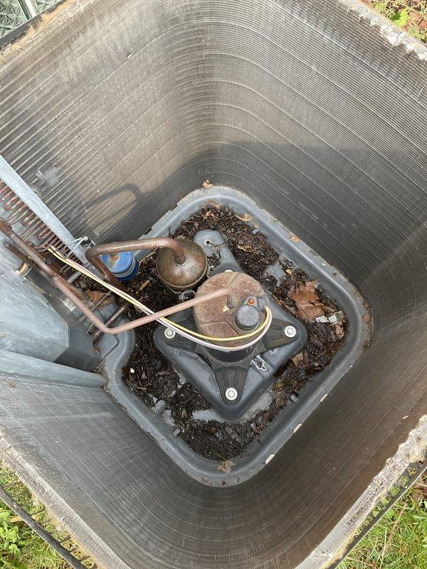 Completed prepaid seasonal air conditioning tune-up on outdoor condensing unit. Performed comprehensive system inspection including electrical connections, refrigerant pressures, and component operation. Removed accumulated organic debris (leaves and dirt) from interior base pan and around fan assembly to ensure proper airflow and prevent motor strain. Inspected copper refrigerant lines, fan motor, and compressor for proper operation. Noted advanced concrete pad deterioration with significant spalling and surface damage, though unit remains structurally supported. All electrical connections tested and secured. System operating within normal parameters with no immediate service needs identified at time of inspection.