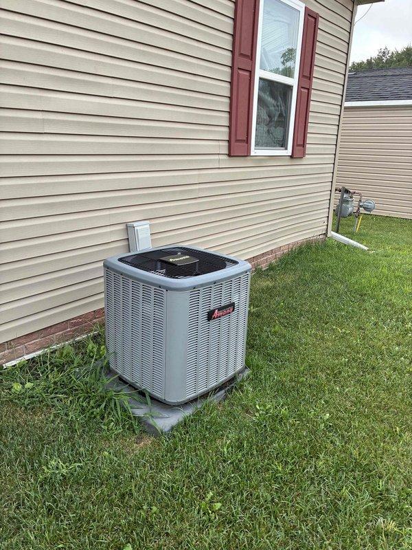 Provided estimate for complete HVAC system replacement including separate furnace and air conditioning unit for residential property. Current system is non-operational and requires full replacement. Equipment is located with outdoor condenser unit positioned on concrete pad adjacent to house foundation, and indoor furnace components accessible through interior space with existing ductwork and ventilation grilles. System utilizes natural gas fuel source for heating operations.