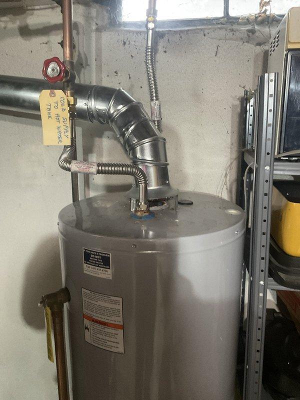 Conducted assessment of existing standard water heater installation in residential basement utility area to provide replacement estimate. Evaluated current working unit with natural draft venting configuration, including inspection of copper supply lines, safety valve assembly, and venting ductwork connections. Documented existing equipment specifications, plumbing connections, and clearance requirements for standard water heater replacement proposal.
