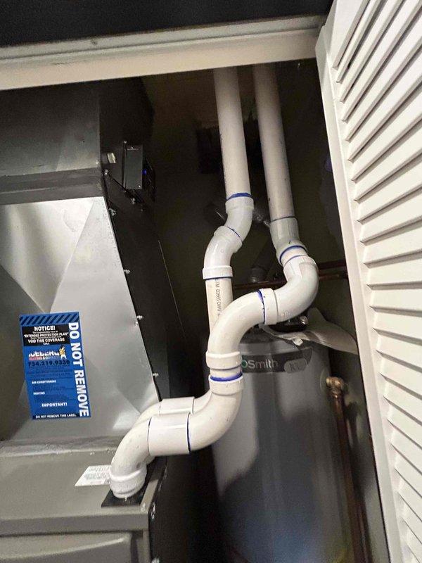 Completed full HVAC system installation including a 2-ton air conditioning unit located in the rear yard and garage air conditioning system. Installed new mechanical equipment with proper PVC condensate drainage lines featuring multiple elbows and properly glued joints with blue marking bands. Reconnected all necessary plumbing connections, flexible lines, and control valves to water heater system in utility closet. All equipment secured, labeled with appropriate safety warnings and energy guides, and tested for proper operation.