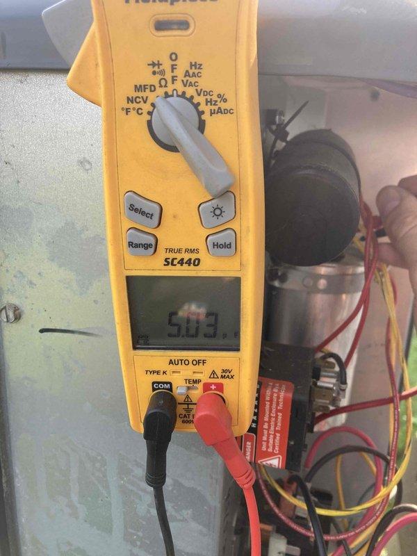 Completed Club AC8-12 preventive maintenance agreement visit on split system air conditioning unit. Performed electrical diagnostics using digital multimeter to verify system voltage and capacitor functionality, confirming proper electrical operation at 5.03 volts on tested component. Inspected and serviced air handler by removing and evaluating foam air filter for debris accumulation and airflow restriction.