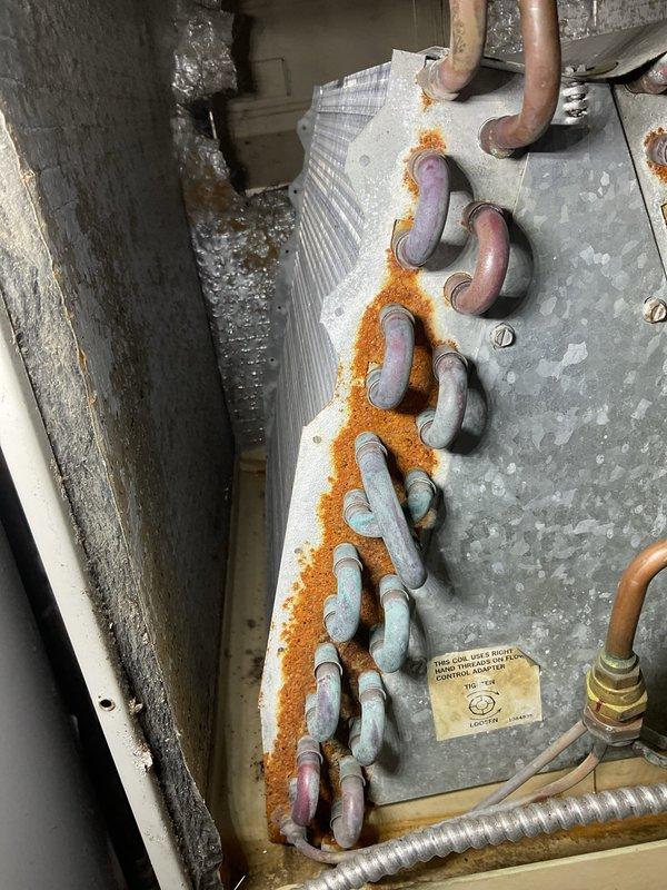 Completed prepaid annual AC tune-up maintenance on residential air conditioning system. Performed comprehensive inspection revealing significant rust and corrosion along refrigerant line connections and evaporator coil assembly, indicating prolonged moisture exposure. Copper refrigerant lines showed oxidation with greenish-blue patina formation, while metal panel surfaces displayed extensive orange-brown rust buildup along pipe seams and mounting points. Evaporator coil fins showed dust accumulation and minor discoloration but remained structurally intact. Documented all corrosion areas with photographs for maintenance records. System currently operational with no reported performance issues, though visible deterioration suggests monitoring for potential refrigerant leaks and continued corrosion progression is recommended for future service visits.