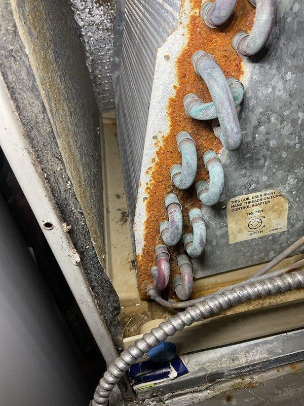 Completed prepaid annual AC tune-up maintenance on residential air conditioning system. Performed comprehensive inspection revealing significant rust and corrosion along refrigerant line connections and evaporator coil assembly, indicating prolonged moisture exposure. Copper refrigerant lines showed oxidation with greenish-blue patina formation, while metal panel surfaces displayed extensive orange-brown rust buildup along pipe seams and mounting points. Evaporator coil fins showed dust accumulation and minor discoloration but remained structurally intact. Documented all corrosion areas with photographs for maintenance records. System currently operational with no reported performance issues, though visible deterioration suggests monitoring for potential refrigerant leaks and continued corrosion progression is recommended for future service visits.