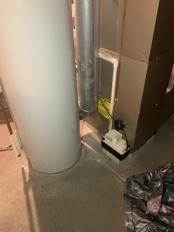 Conducted comprehensive estimate visit for HVAC system replacement, water heater replacement, and air conditioning unit in residential basement utility area. Assessed existing furnace with intake grille, cylindrical water heater with flue pipe and copper connections, and ductwork system including vertical metal duct runs and junction box installations. Documented current equipment conditions and specifications through detailed photography for preparation of replacement quotes covering all three components.