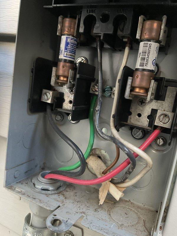 Completed routine preventive maintenance inspection on residential air conditioning system as part of CLUB AC 8-12 agreement. Verified unit levelness using precision leveling tool, inspected outdoor condenser unit condition, and examined electrical disconnect box containing dual cartridge fuses. Documented equipment condition through photographic records showing outdoor unit with protective grille, electrical connections with copper fuses, and associated wiring including ground, line, and neutral conductors. Noted age-related oxidation on electrical components and general dust accumulation consistent with normal operational wear. All critical safety components inspected and system operational status confirmed.