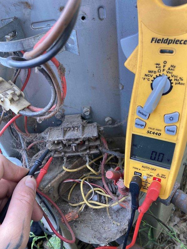 Responded to no cooling complaint on residential air conditioning system. Upon arrival, found unit running but not cooling the home. Performed diagnostic testing and discovered failed contactor with severe corrosion and deterioration preventing proper compressor operation. Contactor showed heavy buildup of dirt, dust, and oxidation affecting electrical connections. Used multimeter to verify 0 volts at contactor, confirming complete electrical failure. Inspected terminal block connections and found extensive cobweb accumulation and aged wiring with signs of neglect. Replaced defective contactor and cleaned electrical connections at terminal block. Removed debris and cobwebs from electrical components. Tested system operation after repairs and verified proper voltage delivery to compressor. Unit now cooling properly with all electrical connections secure and functioning as designed.