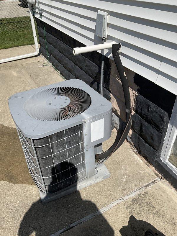 Provided estimate for complete HVAC system replacement including furnace and air conditioning unit. Current system is non-operational with unknown equipment age. Existing installation consists of basement-located gas furnace with associated ductwork, condensate pump, and outdoor condenser unit positioned in below-grade window well with PVC drain line and refrigerant lines running through exterior wall.