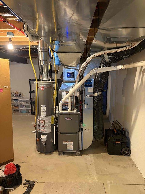 Completed full HVAC system installation including a 70,000 BTU gas furnace and 2-ton air conditioning condenser unit. The furnace was installed in the basement utility area with new white PVC venting routed through the ceiling and proper connection to existing ductwork. The outdoor Bryant condenser unit was positioned on a concrete pad at the rear of the property with appropriate refrigerant line connections, electrical disconnect, and PVC condensate drainage. All mechanical, electrical, and refrigerant connections were completed, system was tested and verified operational upon completion.