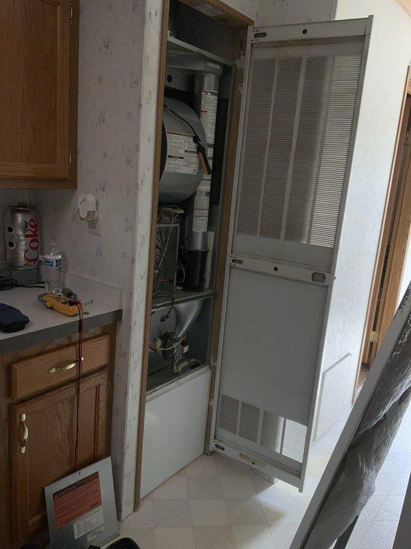 # HVAC Service Call - No Cool Condition

Responded to service call for 20-year-old air conditioning system with no cooling complaint. Upon arrival, performed complete system evaluation of outdoor condensing unit and indoor air handler components.

## Inspection and Findings

Conducted thorough visual inspection of electrical control compartment, revealing aged control circuit board with multiple relays, capacitors, and associated wiring connections. Documented existing wiring configuration showing standard color-coded connections (red, black, white, yellow, blue, green, brown, orange) throughout control box. Noted presence of transformers and relay components within electrical enclosure.

Inspected indoor air handler unit located in utility closet adjacent to kitchen area. Examined furnace/air handler cabinet with louvered door panels designed for proper air circulation. Verified ductwork connections including both flexible and rigid metal sections.

## System Assessment

Given the adv