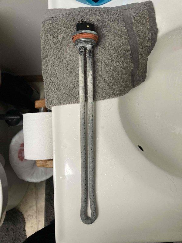 Responded to no hot water complaint on tanked water heater. Upon inspection, found failed lower heating element with heavy mineral buildup and corrosion. Removed defective heating element, verified electrical continuity with multimeter showing open circuit at 139 ohms, confirming element failure. Replaced heating element with new unit including gasket, restored power, and tested system for proper operation.