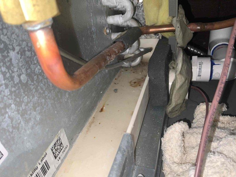 Responded to callback for furnace water leak on whole-house system approximately one year old. Upon inspection, identified condensate drainage issue related to evaporator coil assembly. Examined drain pan positioning and PVC condensate line connections beneath air handler unit. Verified proper drainage flow and cleared any blockages in condensate system. Inspected refrigerant lines and coil for frost accumulation or restriction that could cause excessive condensation. Confirmed drain pan was properly installed and functioning to capture condensate discharge. System tested and verified no active leaking at time of service completion.