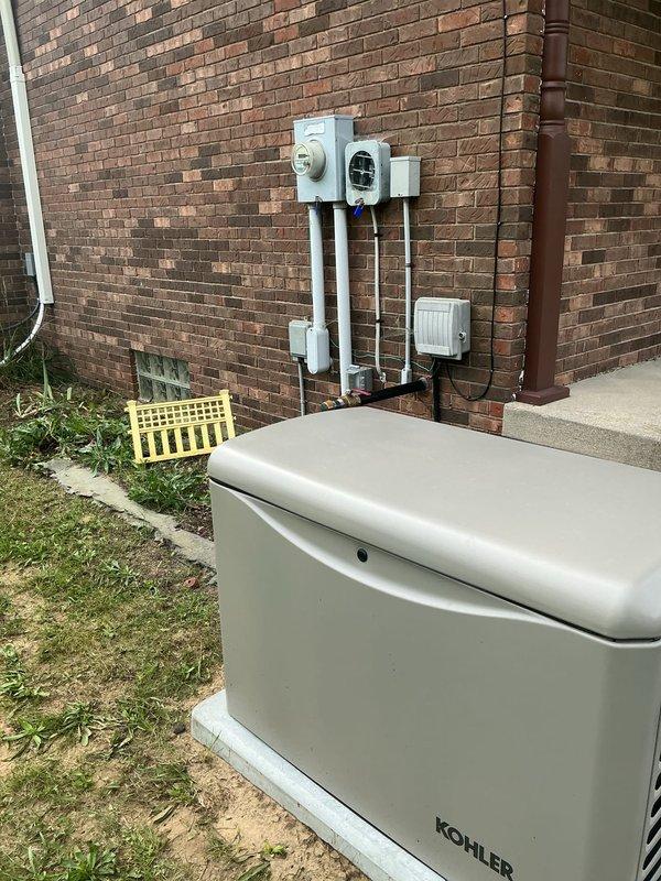 Completed electrical installation of Kohler standby generator unit on concrete pad in rear yard area. Installed exterior electrical components including meter housing, disconnect box, and conduit system with proper vertical runs connecting all electrical panels and equipment. All electrical connections, grounding, and code-compliant wiring completed for generator system integration with existing electrical service.