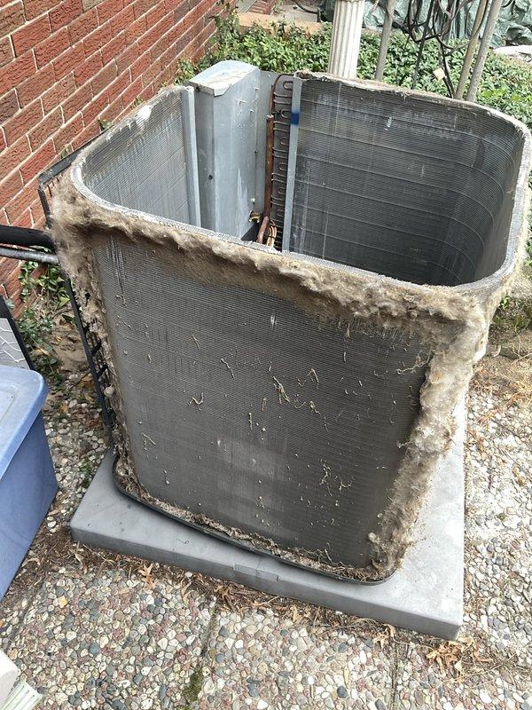Responded to no-cooling call for residential air conditioning system. Upon arrival, found outdoor condenser unit in severely neglected condition with heavy accumulation of dirt, debris, and deteriorated insulation material covering exterior surfaces and top of unit. Condenser coil fins showed significant buildup affecting airflow and heat transfer efficiency. Drain pan contained substantial debris including dirt, gravel, and sediment that could impede proper drainage and potentially cause water damage. Performed comprehensive cleaning of condenser unit exterior, removed deteriorated insulation material, and cleared drain pan of all accumulated debris. Verified unit operation and restored cooling function to system.