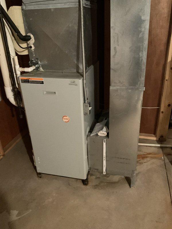Conducted estimate for complete HVAC system replacement in residential basement installation. Existing air conditioning unit found to be low on R22 refrigerant and unable to adequately cool the home, while furnace showed signs of advanced age requiring replacement. Evaluated current system configuration including furnace, ductwork, and air handler arrangement. Documented existing equipment installation with photographic records showing white furnace unit with connected flexible metallic ductwork and adjacent gray sheet metal air handler components. Assessed electrical connections, duct transitions, and overall system layout to provide comprehensive replacement recommendations for both heating and cooling equipment.