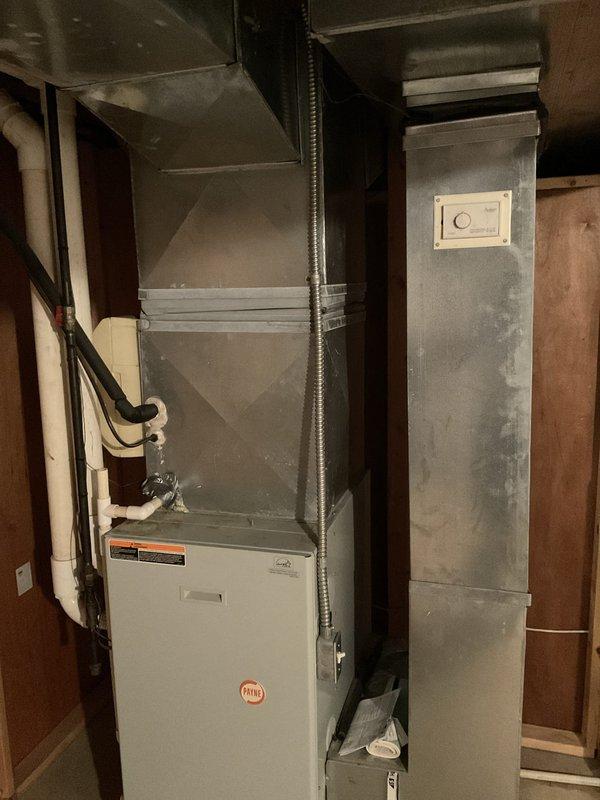 Conducted estimate for complete HVAC system replacement in residential basement installation. Existing air conditioning unit found to be low on R22 refrigerant and unable to adequately cool the home, while furnace showed signs of advanced age requiring replacement. Evaluated current system configuration including furnace, ductwork, and air handler arrangement. Documented existing equipment installation with photographic records showing white furnace unit with connected flexible metallic ductwork and adjacent gray sheet metal air handler components. Assessed electrical connections, duct transitions, and overall system layout to provide comprehensive replacement recommendations for both heating and cooling equipment.