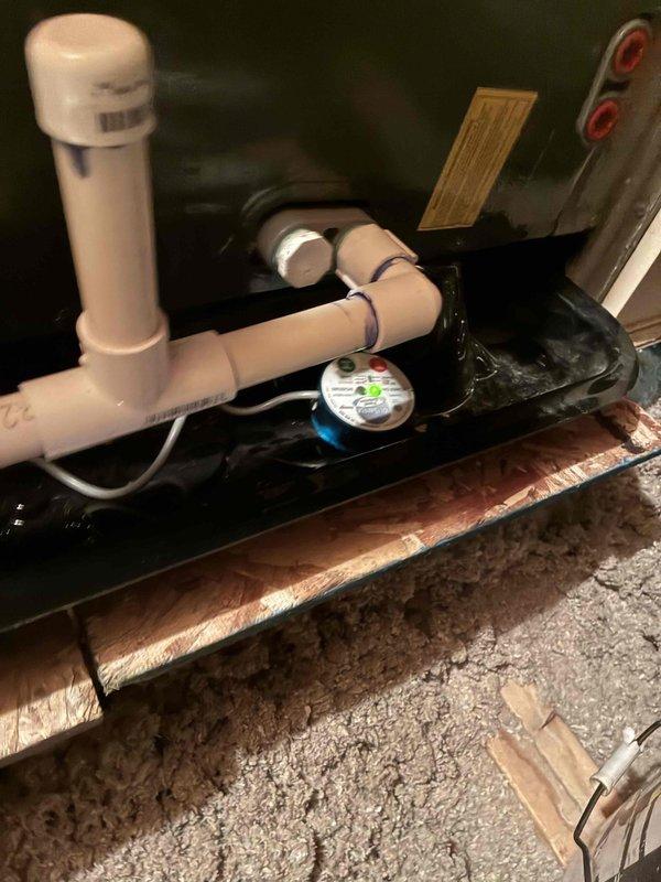 Completed warranty service by removing and replacing the failed condensate drain pan on the attic-mounted HVAC air handler. The new black metal drain pan was properly installed with PVC drainage piping reconnected and the condensate safety switch remounted in the pan to ensure proper overflow protection and system shutdown capability if needed.