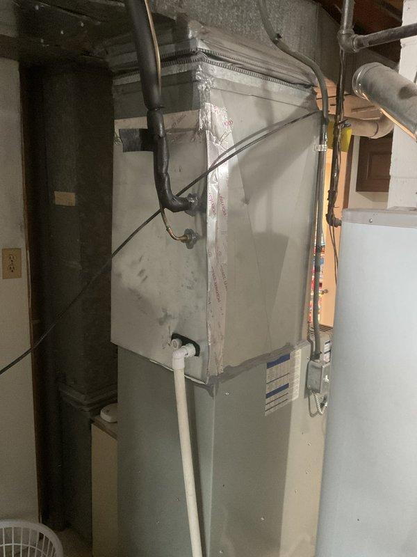 Conducted comprehensive HVAC system evaluation for failed heat exchanger in existing furnace and 14-year-old air conditioning system. Inspected basement-installed furnace unit with vertical air handler configuration, documented existing equipment condition including ductwork connections, copper refrigerant lines, and electrical components mounted on auxiliary board. Photographed current system setup showing insulated supply ducts, PVC condensate drainage, and mechanical room infrastructure. Provided detailed replacement options for both heating and cooling equipment, presenting available promotional opportunities for complete system upgrade versus single component replacement to address the compromised heat exchanger while considering the age and remaining service life of the existing AC unit.