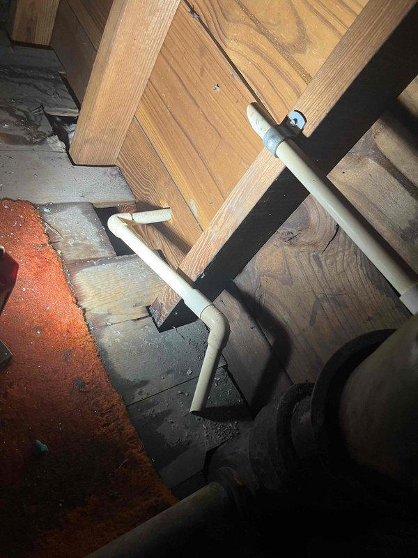 # Emergency Water Leak Response - HVAC System

Responded to emergency service call for major water leak originating from attic-mounted air conditioning unit. Upon arrival, found active water intrusion had caused ceiling collapse in living space with water penetrating through light fixtures, creating immediate safety hazard. System age confirmed at approximately two to five years old.

Conducted thorough inspection of affected areas including attic space and water-damaged ceiling sections. Documented extensive water damage to ceiling materials and structural components. Photographed underside of floor structure showing exposed wooden joists, PVC drainage piping, and plumbing connections to establish leak source and extent of damage. Identified condensate drain line failure as primary cause of water overflow from air handler unit.

Assessed HVAC equipment condition and verified condensate drainage system malfunction. Evaluated structural integrity of affected wooden framing members and f