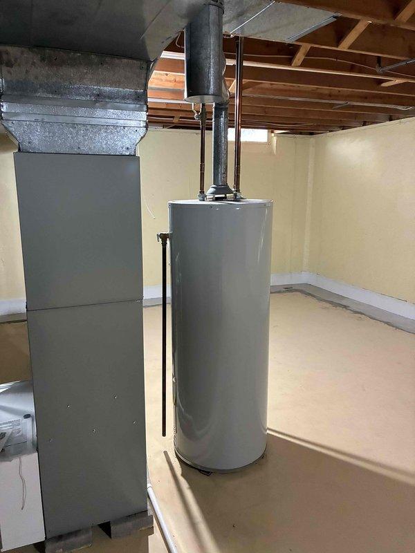 Conducted on-site evaluation of existing HVAC system for complete replacement estimate. Assessed current furnace and air conditioning equipment located in basement utility area, documenting equipment age, condition, and configuration. Photographed existing gray rectangular furnace unit with connected ductwork, cylindrical water heater, and associated piping systems including copper lines and PVC venting. Evaluated mechanical room layout, ceiling clearances with exposed joists, and concrete flooring for equipment access and replacement feasibility. Reviewed furnace specifications and warning labels, noting current installation setup with white PVC exhaust pipes, metal ductwork routing, and humidifier integration. Documented all necessary measurements and equipment specifications to prepare comprehensive replacement proposal for new furnace and air conditioning system.