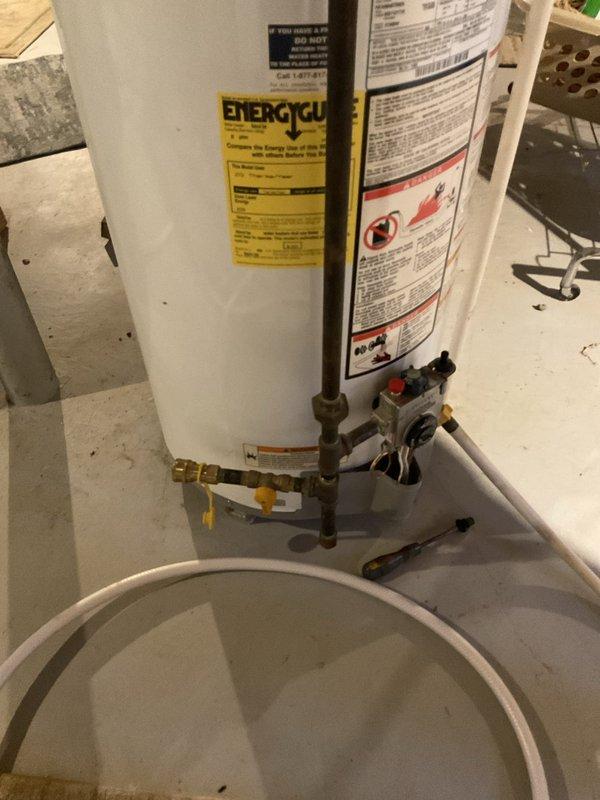 Performed estimate for replacement of non-functioning tanked water heater in residential basement utility room. Assessed existing Whirlpool unit with gas control valve assembly, copper and brass plumbing connections, and natural draft venting configuration. Documented current installation including pipe connections, shut-off valves, and drain pan positioning to provide accurate replacement specifications for standard tank-style water heater.