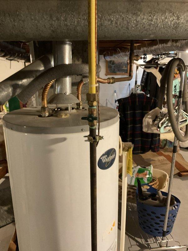 Performed estimate for replacement of non-functioning tanked water heater in residential basement utility room. Assessed existing Whirlpool unit with gas control valve assembly, copper and brass plumbing connections, and natural draft venting configuration. Documented current installation including pipe connections, shut-off valves, and drain pan positioning to provide accurate replacement specifications for standard tank-style water heater.