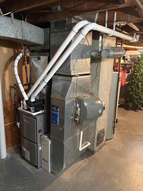 Completed full HVAC system installation including a 70,000 BTU furnace and 2-ton rear-discharge air conditioning unit with mechanical and electrical connections. Installed humidifier and reconnected existing electrical components. Removed fan motor from AC unit per customer request and left on-site for customer retention. All equipment properly installed, tested, and operational with PVC venting and drainage lines routed appropriately in basement utility area.