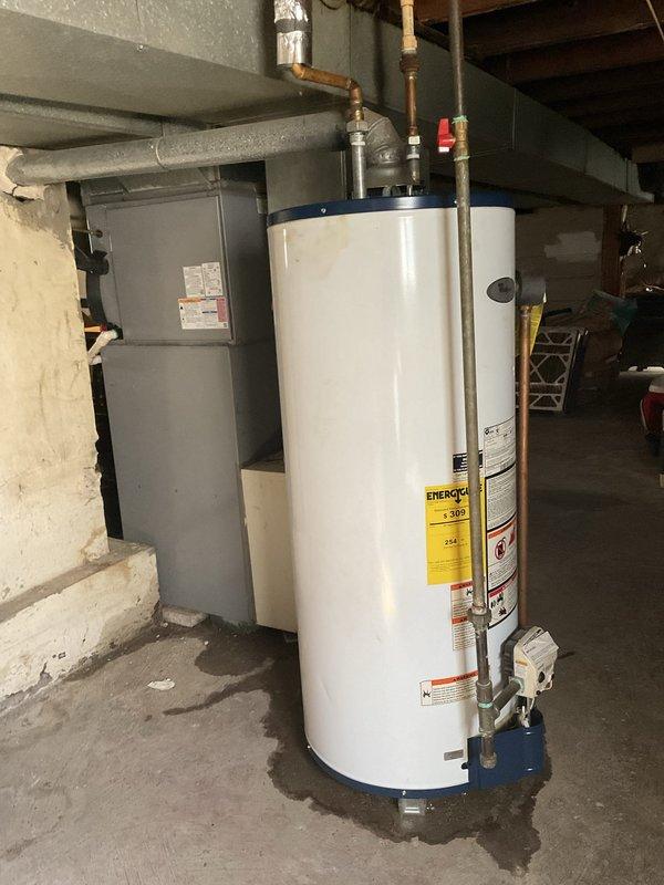 Responded to no hot water complaint and inspected tanked water heater installation in basement utility area. Upon arrival, found water heater with visible moisture staining at base and confirmed lack of hot water production. Evaluated copper supply line connections, shutoff valves, and galvanized piping assembly at top of unit. Assessed water heater condition, checked pilot light status, and verified proper gas supply and venting configuration. Performed necessary repairs to restore hot water service and tested system operation to ensure proper function before departure.