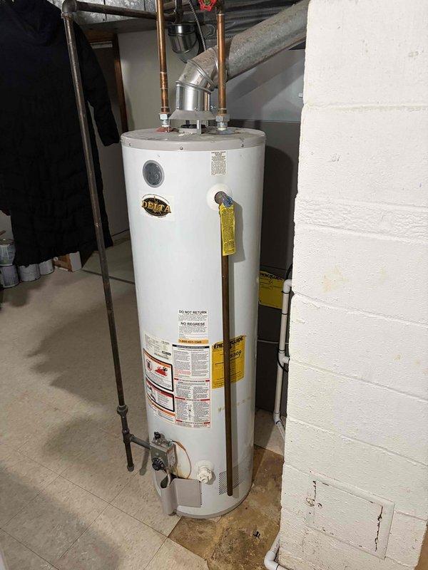 Completed full HVAC system installation including new air handler unit and water heater in basement utility area. Installed gray metal air handler with associated white component cabinet, connected all necessary ductwork, and positioned new vertical tank-style water heater with proper copper piping configuration including temperature/pressure relief valve and drain valve. All equipment mounted on concrete floor against prepared wall surfaces, system tested and verified operational, financing documentation completed and identification verified on file.