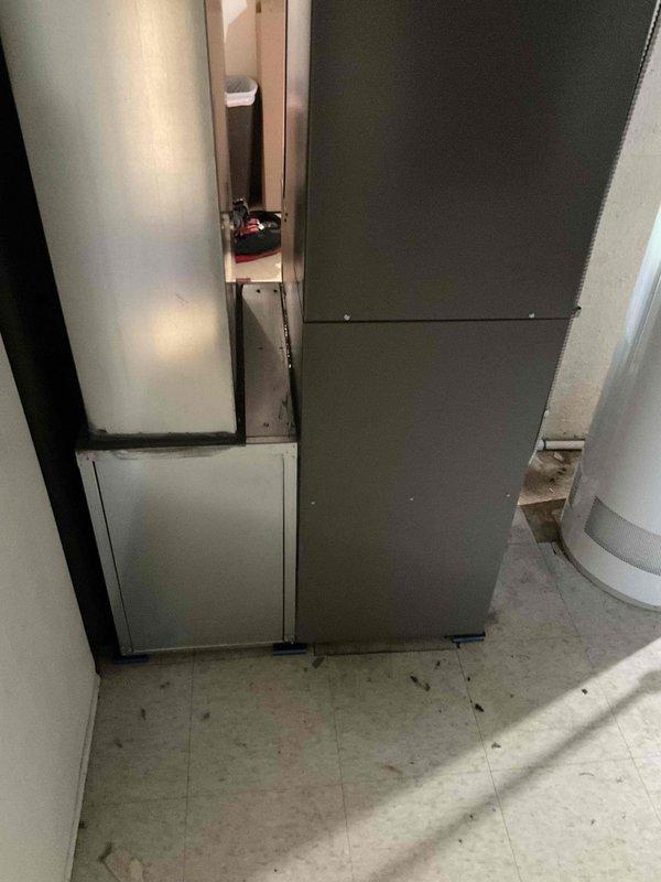 Completed full HVAC system installation including new air handler unit and water heater in basement utility area. Installed gray metal air handler with associated white component cabinet, connected all necessary ductwork, and positioned new vertical tank-style water heater with proper copper piping configuration including temperature/pressure relief valve and drain valve. All equipment mounted on concrete floor against prepared wall surfaces, system tested and verified operational, financing documentation completed and identification verified on file.