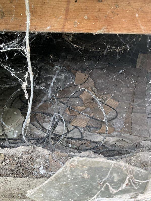 Conducted crawl space inspection to assess HVAC system components and ductwork conditions. Documented existing flexible ductwork installation beneath floor joists, noting accumulation of dust, debris, and cobwebs throughout the area indicating need for system cleaning and potential air quality concerns. Photographed insulation placement and overall crawl space environment to recommend future maintenance and filtration improvements.