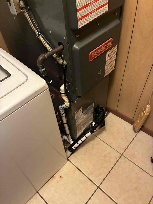 Completed installation of a 2.5-ton Amana air conditioning system with outdoor condenser unit positioned on exterior pad and Goodman air handler mounted in interior utility closet. Established refrigerant line connections, electrical service, and condensate drainage system with PVC piping to ensure proper system operation and code compliance.