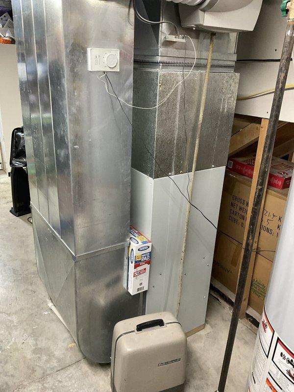 Conducted comprehensive evaluation of 24-year-old residential HVAC system for replacement estimate. Assessed existing furnace and ductwork assembly located in basement utility area, documented current equipment configuration including galvanized metal ductwork, thermostat controls, PVC drainage system, and condensate collection setup. Inspected exterior components and evaluated installation access points to provide complete system replacement recommendations.