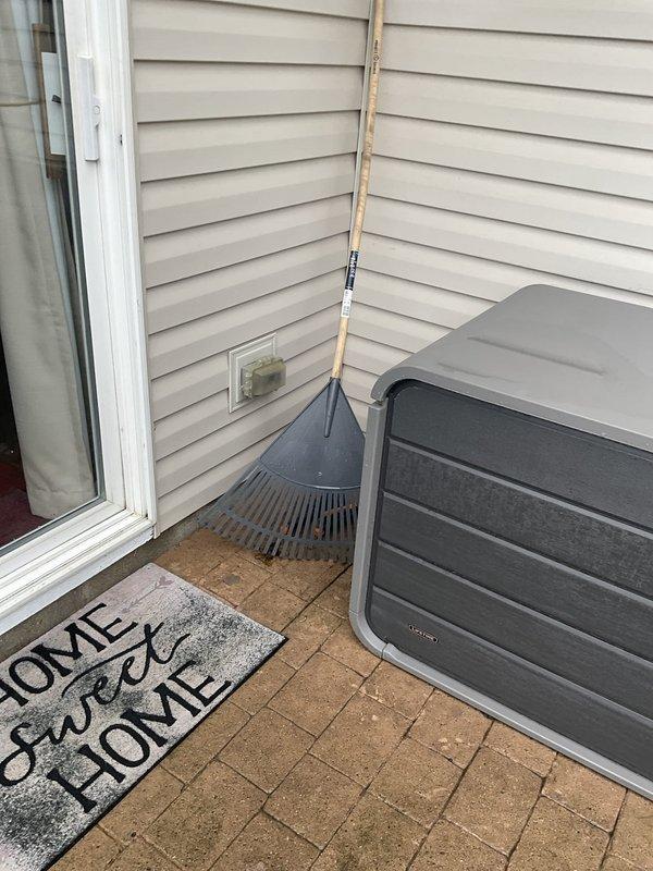 Conducted on-site evaluation of existing outdoor air conditioning unit with cylindrical condenser configuration and white top panel. Assessed current system condition, documented equipment specifications, and photographed installation for replacement estimate preparation. Unit located on concrete paver patio against vinyl-sided residence with PVC refrigerant line set routing along exterior wall.