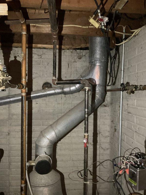 Conducted estimate for replacement of 30-year-old natural gas-fired hot water boiler system serving baseboard heating distribution. Evaluated existing installation including copper piping manifold, electrical controls, zone valves, and PVC venting configuration. Documented current system layout with aged copper supply and return lines, electrical relay components, and mechanical room conditions to provide accurate replacement specifications for new high-efficiency boiler installation.
