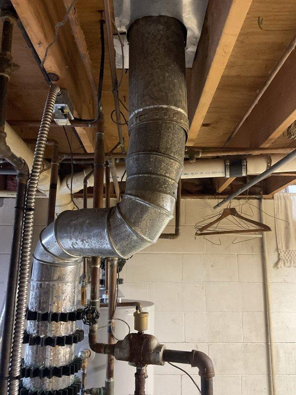 Conducted comprehensive assessment of 34-year-old boiler system and provided replacement options to homeowner. Identified critical safety concerns including failed pressure relief valve requiring immediate replacement and missing backflow preventer that must be installed to bring system into code compliance. Documented condition of aging 18-year-old domestic hot water tank. Photographed existing ductwork, piping infrastructure, and mechanical systems in utility space to support estimate preparation for complete boiler replacement.