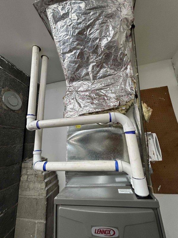Completed full mechanical HVAC system installation featuring a Lennox 90,000 BTU furnace in utility room. System includes properly configured PVC venting, insulated refrigerant lines with secure mounting, and connected ductwork. All components tested and operational, with refrigerant charge verified at proper levels using calibrated instrumentation.