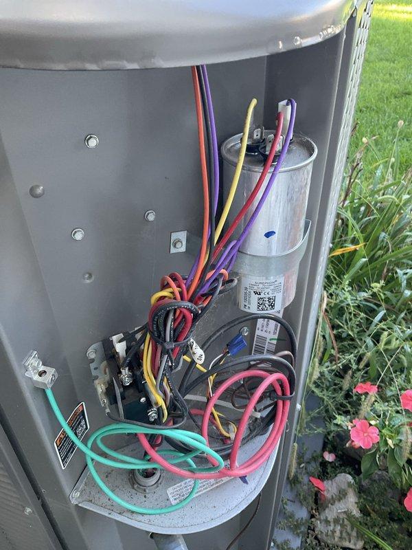 Completed preventative maintenance inspection on residential outdoor air conditioning unit as part of Club AC8-12 agreement. Performed comprehensive system evaluation including visual inspection of condenser unit exterior, electrical components, capacitor, contactor, and wiring connections. All electrical connections found secure with proper color-coded wiring intact. Capacitor and contactor operating within normal parameters. Unit exterior showing typical environmental weathering with dirt and mineral deposit accumulation on casing. Condenser coils and fins accessible through top opening appear functional with age-appropriate darkening. System mounted securely on concrete pad with no structural concerns noted. Equipment photographed for service records documenting current condition of exterior cabinet and internal electrical compartment components.
