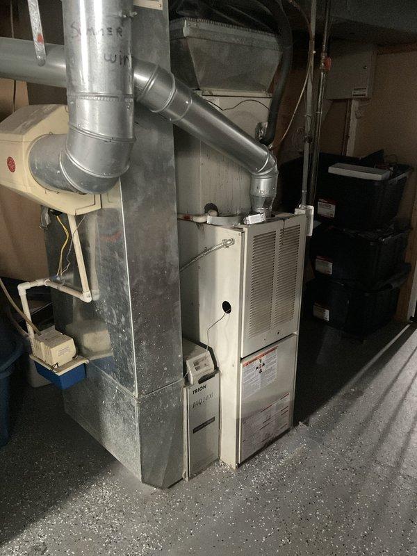 Conducted on-site evaluation of existing residential furnace system in basement utility area for replacement estimate. Inspected current beige/cream-colored furnace unit with associated ductwork, metal plenum, and vertical supply connections. Documented equipment condition, ductwork configuration, and installation space parameters through photographic assessment to provide accurate replacement recommendations and system specifications.