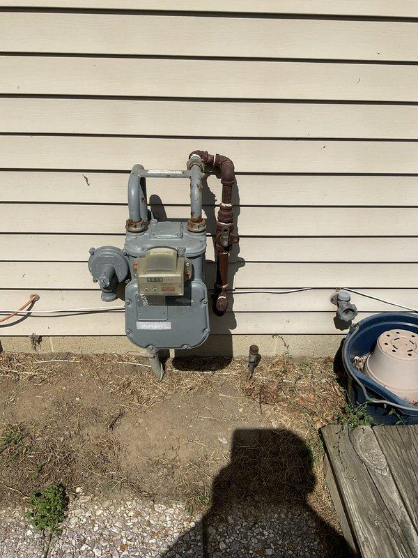 Completed electrical estimate for new whole home generator installation at manufactured home. Assessed existing natural gas meter and supply infrastructure, noting aged piping with corrosion on existing gas lines that will require consideration during installation planning. Documented 40-gallon Bradford White natural gas water heater (Model MI40T6FBN, 40,000 BTU/hr input) to evaluate total gas demand and verify adequate capacity for generator addition to existing natural gas system.