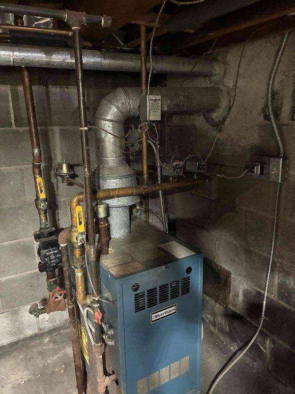 Completed estimate for replacement of aging Weil-McLain boiler system currently installed in basement mechanical room. Existing unit is approximately 12 years old and still operational, with associated copper piping, valve controls, and distribution components showing normal signs of age and surface oxidation. Assessed complete heating system infrastructure including ductwork, piping configuration, and electrical panel to provide comprehensive replacement recommendations.