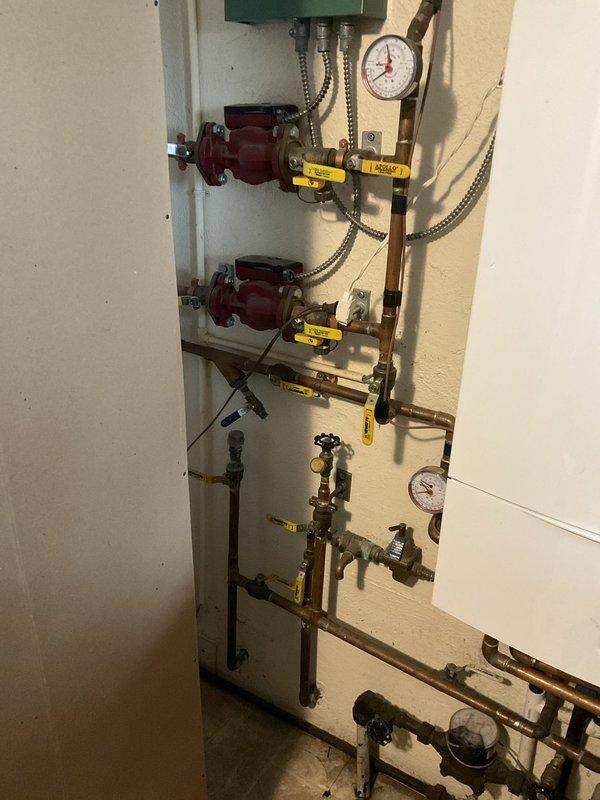 Conducted on-site evaluation of existing Bosch ZWB 42-3 direct-vent propane combi boiler system installed approximately 2015, currently providing both baseboard heating and domestic hot water with no operational issues reported. Documented current installation configuration including copper piping network, dual circulator pumps with expansion loops, multiple isolation valves, pressure gauges, and venting arrangement in basement mechanical room. Photographed complete system layout showing wall-mounted boiler unit, manifold assembly with brass fittings and yellow-handled ball valves, and all associated connections to assess scope of replacement work. Prepared comprehensive estimate for complete system replacement including removal and disposal of existing combi boiler, installation of new high-efficiency combi unit such as Burnham Alta Combi 200K BTU, all necessary materials and components, modifications to existing venting and piping systems as required, reconnection of baseboard heatin