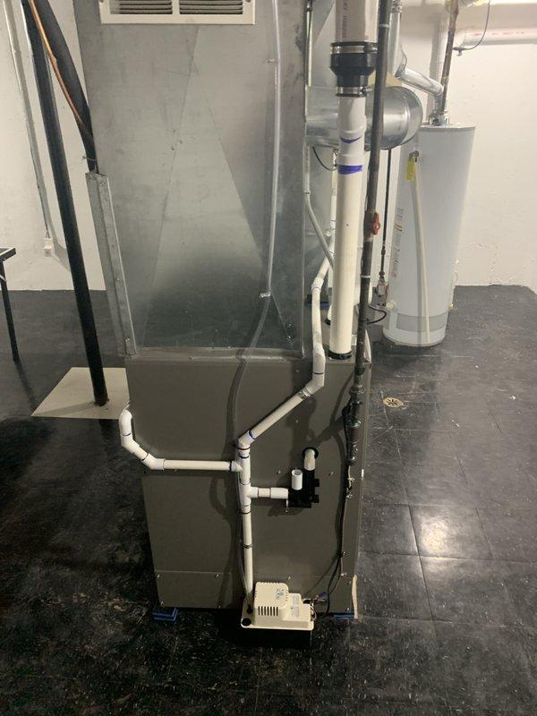 Successfully installed a new 110,000 BTU furnace in the basement utility area with complete mechanical hookup. Configured and connected white PVC venting system with proper routing and support, reconnected all electrical components including conduit and wiring, and integrated condensate pump for drainage. The furnace was positioned adjacent to the existing water heater with proper clearances maintained, all ductwork connections were secured at the plenum junction, and the system was tested for proper operation upon completion.