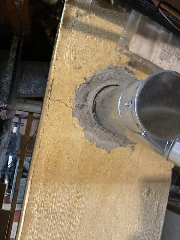 Responded to service call for non-functioning standard water heater with active leak. Upon inspection, confirmed existing Whirlpool unit was leaking and required replacement. Provided estimate for standard water heater replacement in basement utility area. Assessed existing natural draft venting system with metal duct penetrating through ceiling, noting proper sealing with gray sealant material. Documented current installation configuration including gas line connections, plumbing connections, and drainage setup with catch basin in place. Evaluated surrounding framing and floor conditions to ensure proper clearances and support for new unit installation.