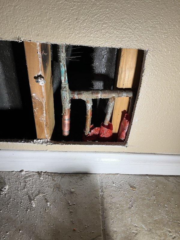 Performed leak detection investigation on a wall cavity with suspected water intrusion. Cut inspection access hole revealing copper pipes with visible T-joint/elbow connections. Documented extensive water damage including deteriorated wooden framing elements, significant mold growth, and moisture-affected insulation. Source of leak appears to be at pipe junction point where severe deterioration was observed.