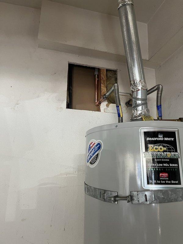 Performed leak detection inspection at customer's residence during renovation work. Located water intrusion source behind drywall near the Bradford White Eco Defender water heater installation. Created access openings in wall to inspect copper supply lines and identified pinhole leak in pipe fitting. Repaired affected section and verified system integrity before closing inspection.
